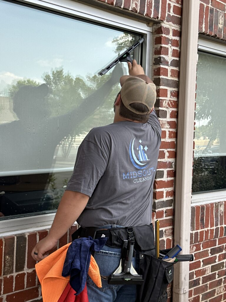 Midsouth Cleaning professional performing commercial window cleaning using a squeegee for a streak-free finish.